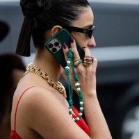Bettina Looney talking on the phone wears sunglasses, golden necklace, red dress outside Prada during the Milan Fashion Week Womenswear Fall/Winter...