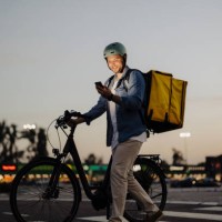 bike courier on city street with delivery box on back using smart phone - junk food stock pictures, royalty-free photos & images