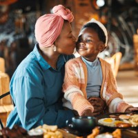 black family, restaurant and eating with mom kiss and child together with bonding, food and care. love, diner and table with burgers and happy girl with lunch and hungry people in a cafe with drink - food stockfoto's en -beel