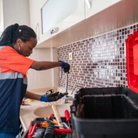 black female plumber fixing a leak in the kitchen sink of a house - home decoration stock pictures, royalty-free photos & images