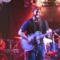 black male guitarist singing and playing acoustic guitar on stage - concert stock pictures, royalty-free photos & images
