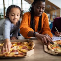 black woman and her family having pizza for lunch at home - junk food stock pictures, royalty-free photos & images