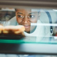 black woman, bakery customer and glass for dessert, cake or sweet food from retail, store or grocery shop. woman, happy and shopping in supermarket, mall or cafe for discount, sale or deal with smile - junk food stock picture