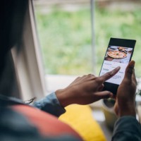 black woman in her home, ordering food online through a mobile app on her phone - food stock pictures, royalty-free photos & images