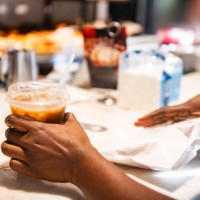 black woman's hands picking up iced coffee and snack from take out counter - junk food stock pictures, royalty-free photos & images