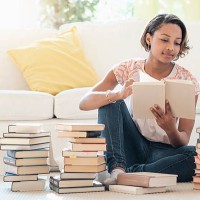 black woman sitting on floor reading pile of books - home decoration stock pictures, royalty-free photos & images