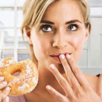 blonde woman eating a sugar coated doughnut - junk food stock pictures, royalty-free photos & images