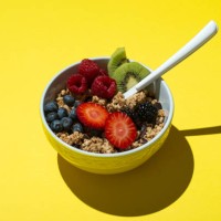 bowl with muesli ,chocolate and fruits on on yellow background - food stock pictures, royalty-free photos & images