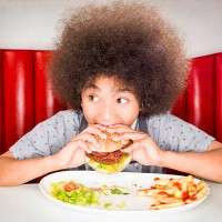 boy (10-11) eating hamburger in american diner - junk food stock pictures, royalty-free photos & images