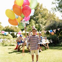 boy (5-7) holding bunch of balloons outdoors, friends in background - garden decoration stock pictures, royalty-free photos & images