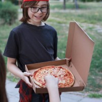 boy and girl are having fun while eating pizza on a park - junk food stock pictures, royalty-free photos & images