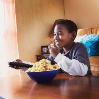 boy eating popcorn and watching tv - junk food stock pictures, royalty-free photos & images