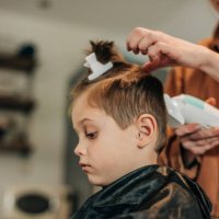 boy getting hair cut by mother at home - hairstyle stockfoto's en -beelden