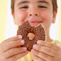 boy holding fresh sweet glazed donut in hands - junk food stock pictures, royalty-free photos & images