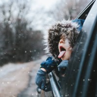 boy on a road trip. the little boy is looking from the car window in winter , opened his mouth and pulled out his tongue, catches snowflakes - travel stock pictures, royalty-free photos & images