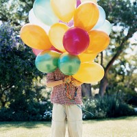 boy standing on lawn behind a bunch of balloons obscuring his face - garden decoration stock pictures, royalty-free photos & images
