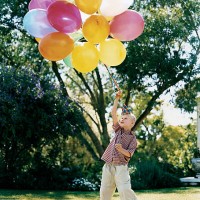 boy standing on the lawn holding a bunch of balloons - garden decoration stockfoto's en -beelden