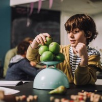 boy weighing fruits on weight scale at desk in classroom - food stock pictures, royalty-free photos & images