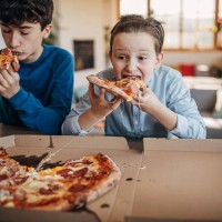 boys eating pizza together - junk food stock pictures, royalty-free photos & images