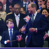 Britain's Prince George of Wales reacts as his father Britain's Prince William, Prince of Wales plays with a Union flag during the Coronation Concert...
