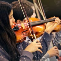 brunette girl playing the violin in a children's music band - concert stock pictures, royalty-free photos & images