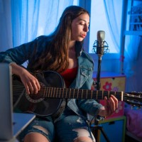 brunette teen singer girl singing in microphone playing guitar teleconferencing - concert stock pictures, royalty-free photos & images
