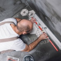 builder leveling the tiles on the bathroom floor - home decoration stock pictures, royalty-free photos & images