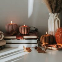 burning candles shape of pumpkin, stack knitted season sweaters, daily and autumn leaves. cozy autumn lifestyle, hygge concept. still life - home decoration stock pictures, royalty-free photos & images