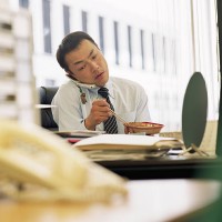 businessman eating lunch at desk, using mobile phone - junk food stock pictures, royalty-free photos & images