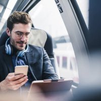 businessman in train with cell phone, headphones and tablet - travel stock pictures, royalty-free photos & images