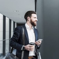 businessman walking in office building while talking on the phone with ear phones - junk food stock pictures, royalty-free photos & images