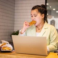 businesswoman eating fried chicken while working with laptop - junk food stock pictures, royalty-free photos & images