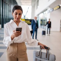 businesswoman using a smartphone in an airport terminal - travel stock pictures, royalty-free photos & images