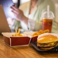businesswoman working at laptop with fast food on restaurant table - junk food stock pictures, royalty-free photos & images