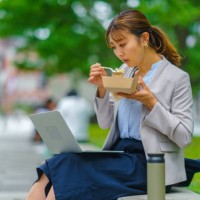 businesswoman working on laptop while having lunch in the city - junk food stock pictures, royalty-free photos & images