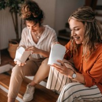 businesswomen eating food sitting on stairs during lunch break at office - junk food stock pictures, royalty-free photos & images