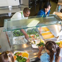 cafeteria worker serving trays of healthy food to children - food stock pictures, royalty-free photos & images