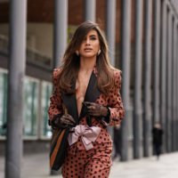 Camila Coelho wears light pink heart shaped earrings, dark brown black polka dotted light pink bow Valentino blazer jacket, black dark brown pattern...