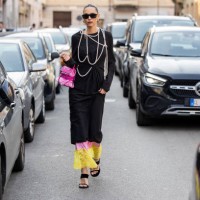 Candela Pelizza wears pink bag, black dress, pearl necklace outside Moschino during the Milan Fashion Week Womenswear Fall/Winter 2025/2026 on...