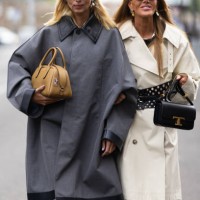 Candela Pellizza wears a beige leather bag, silver eerrings and a grey long coat with leather applications on it and Anna dello Russo wears black...