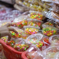 candy store front with colorful candies and sugar coated fennel being picked up by a kid. - junk food stock pictures, royalty-free photos & images