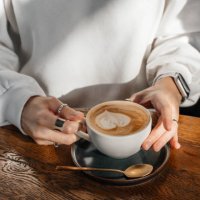 cappuccino in a white ceramic cup on a wooden table. close-up. - coffee stockfoto's en -beelden