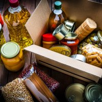 cardboard box filled with non-perishable foods on wooden table. high angle view. - food stock pictures, royalty-free photos & images