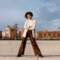 carefree afro woman with arms crossed posing on retaining wall against buildings in city - fashion stock pictures, royalty-free photos & images