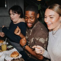 carefree male and female friends having fun while having snacks on table at nightclub - food stock pictures, royalty-free photos & images
