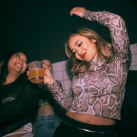 carefree young woman with drink dancing by female friend enjoying at nightclub - concert stock pictures, royalty-free photos & images