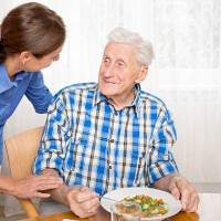 caregiver with senior man, helping eating - food stock pictures, royalty-free photos & images