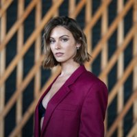 Carmella Rose wears light brown wavy short hair, black bralette, burgundy bordeaux oversized blazer jacket, outside Stella McCartney, during the...