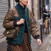 Caroline Issa wears brown jacket with green checked details, olive green Chloe bag, brown and blue striped pleated skirt, outside Chloe, during the...