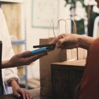 cashier, customer and phone with pos on machine, fintech or digital payment at store or small business retail. people, hands and clothes seller, point of sale on mobile app, tap and shopping bag - fashion stock pictures, roya